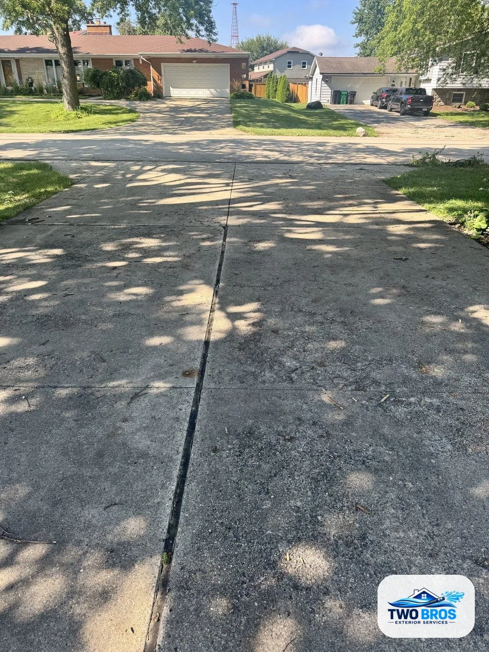 Driveway before cleaning, showing dark dirt and tire stains
